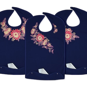 May include: Three navy blue bibs with a floral design in shades of pink, red, and yellow. Each bib has a pocket on the bottom.