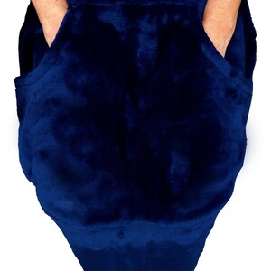 Puede incluir: Una manta con capucha azul oscuro con dos bolsillos grandes. La manta est&aacute; hecha de un material suave y afelpado.
