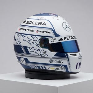 Puede incluir: Un casco de carreras blanco y azul con un patrón de estrellas en el lateral. El casco muestra varios logotipos de marcas, incluidos Solera, Crowdstrike, G42, Petronas, Adidas, Signify y Akkodis, junto con una visera tintada azul y el emblema Mercedes.