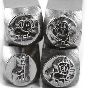 May include: Close-up of four metal stamps with animal designs. The stamps feature an elephant, a monkey, a giraffe, and a lion. Each animal is depicted in a cartoon style, with detailed features. The stamps are silver in color and appear to be new.