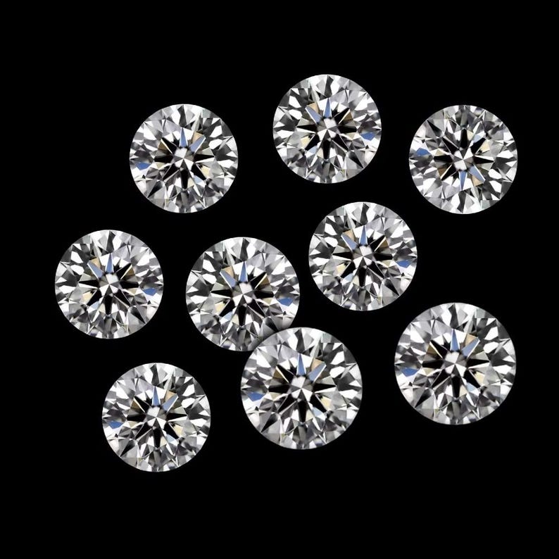 May include: Nine round-cut diamonds on a black backdrop. The clear diamonds sparkle, with many facets reflecting light. The arrangement is scattered, highlighting the brilliance of the gemstones. Each diamond is a perfect circle.