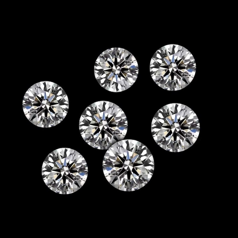 May include: Seven round-cut diamonds are shown against a black backdrop. The diamonds are clear and sparkling, with multiple facets reflecting light. The arrangement is scattered, showcasing the brilliance of the gemstones.