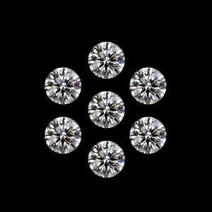 May include: Seven round-cut diamonds arranged in a circular pattern against a black background. The diamonds are clear and sparkling, reflecting light. The image showcases the brilliance and facets of the gemstones.