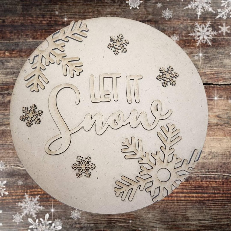 May include: A round wooden sign with the words "Let It Snow" in a cursive font. The sign is decorated with snowflakes cut out of the wood.