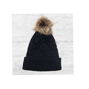 May include: Black knit beanie with a brown faux fur pom pom.