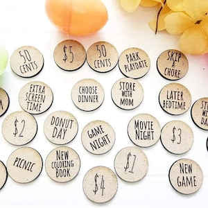 May include: A set of 20 wooden tokens with various activities and rewards written on them. The tokens are brown and have black text. Some of the activities include "Ice Cream", "New Book", "Donut Day", "Game Night", "Movie Night", "Store with Dad", "Friend Playdate", "Skip a Chore", "Later Bedtime", "Store with Mom", "Choose Dinner", "Extra Screen Time", "50 Cents", "$5", "$2", "$3", "$1", "$4", "Park Playdate", "New Game", "Sweet Treat", "Picnic", "New Coloring Book".