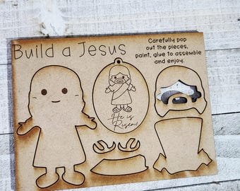May include: A wooden craft kit labeled "Build a Jesus" with pre-cut shapes of Jesus and the text "He is Risen!" Instructions read "Carefully pop out the pieces, paint, glue to assemble and enjoy."