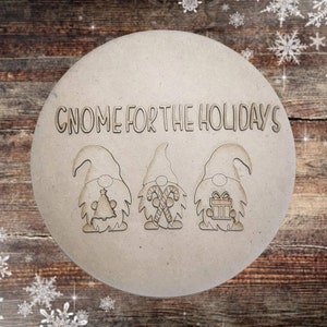 May include: A round wooden sign with the text "Gnome for the Holidays" and three gnomes with different holiday decorations. The gnomes are holding a Christmas tree, candy canes, and a gift box.