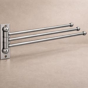Peut inclure: Un porte-serviettes mural chromé avec trois barres rotatives. Le support a une base rectangulaire avec des détails arrondis, conçu pour une utilisation dans la salle de bain. Les barres sont espacées uniformément avec des extrémités arrondies.