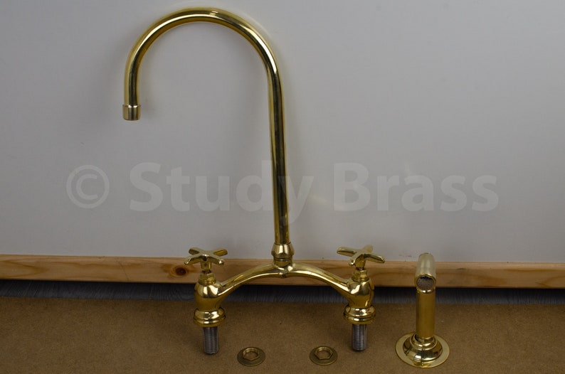 以下が含まれることがあります： 高アーチの注ぎ口と2つのハンドルが付いた金メッキのキッチン蛇口。蛇口はカウンタートップに取り付けられており、磨かれた仕上げになっています。