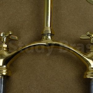 以下が含まれることがあります： 湾曲した注ぎ口と十字形のハンドルが付いた、金色のダブルハンドル蛇口です。