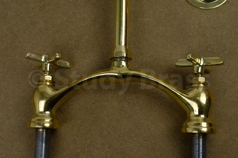 以下が含まれることがあります： 湾曲した注ぎ口と十字形のハンドルが付いた、金色のダブルハンドル蛇口です。