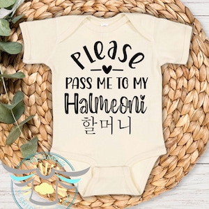 May include: A cream-colored baby onesie with black text that reads "Please pass me to my Halmeoni 할머니".
