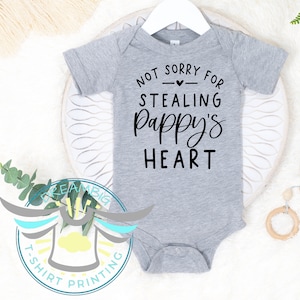 May include: Gray baby onesie with black text that reads "Not sorry for stealing Pappy's heart".
