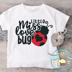 May include: White t-shirt with black text that reads "Miss Little Love Bug" and a red and black ladybug graphic.