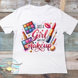May include: White t-shirt with a colorful graphic design featuring makeup items like lipstick, eyeshadow palettes, and a heart. The text reads "Just a Girl Who Loves Makeup".