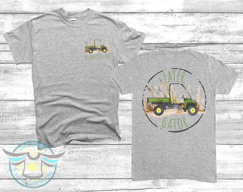 May include: Grey t-shirt with a green utility vehicle graphic and the text "Backwoods Boy" on the front. The back of the shirt has a green utility vehicle graphic inside a circle with the text "Later Gator".