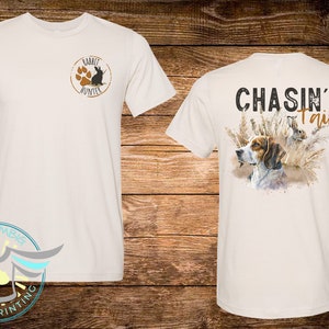 May include: White t-shirt with a brown rabbit hunter logo on the front and the text "CHASIN' Tail" with a brown and white dog and a rabbit in tall grass on the back.