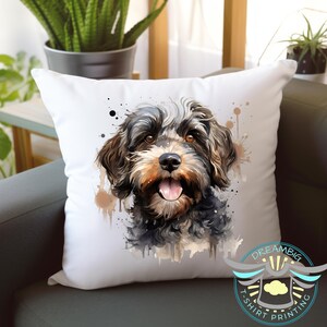 May include: White square throw pillow featuring a watercolor-style portrait of a dog with brown, black, and tan fur. The dog has its tongue out and is smiling. Brown and black paint splatters are around the dog's head. The pillow is on a gray couch.