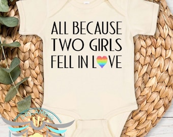 May include: A white baby onesie with the text "All because two girls fell in love" and a rainbow heart.