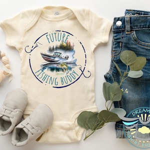 May include: A cream-colored baby onesie with a blue circle graphic that says "Future Fishing Buddy" and a watercolor illustration of a boat, fish, and fishing hook.