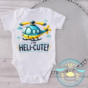 May include: White baby bodysuit with a cartoon helicopter graphic and the text "I'm Heli-Cute!" printed on the front.