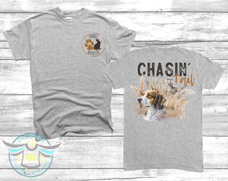 May include: Grey t-shirt with a paw print and rabbit graphic on the front and the text "CHASIN' Tail" with a dog and rabbit graphic on the back.