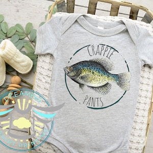 May include: A gray baby onesie with a green circle graphic featuring a black and green crappie fish and the text "Crappie Pants".
