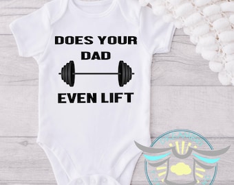 May include: A white short-sleeved baby bodysuit featuring the black text DOES YOUR DAD EVEN LIFT centered on the chest. Between the words DAD and EVEN is a graphic illustration of a black barbell with weight plates on each side.