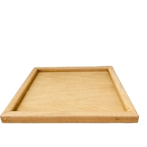 May include: A rectangular wooden tray with a light brown finish. The tray has a raised edge and a smooth surface.