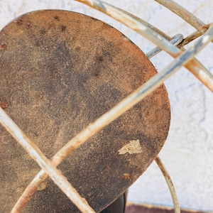 Pu&ograve; includere: Primo piano di una ventola in metallo arrugginito con una pala circolare marrone. La ventola &egrave; realizzata in filo metallico e ha un design semplice.