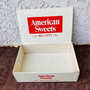 May include: White cardboard box with a red and white logo that says "American Sweets" and "Blunts". The box is open and empty.
