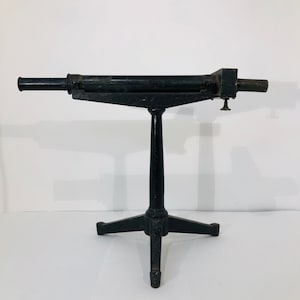 May include: A black vintage telescope on a tripod stand. The telescope has a brass focusing knob and a black metal body.