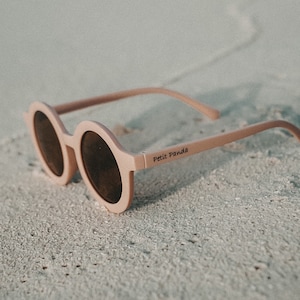 May include: Pink round sunglasses with brown lenses and the text "Petit Panda" on the side.