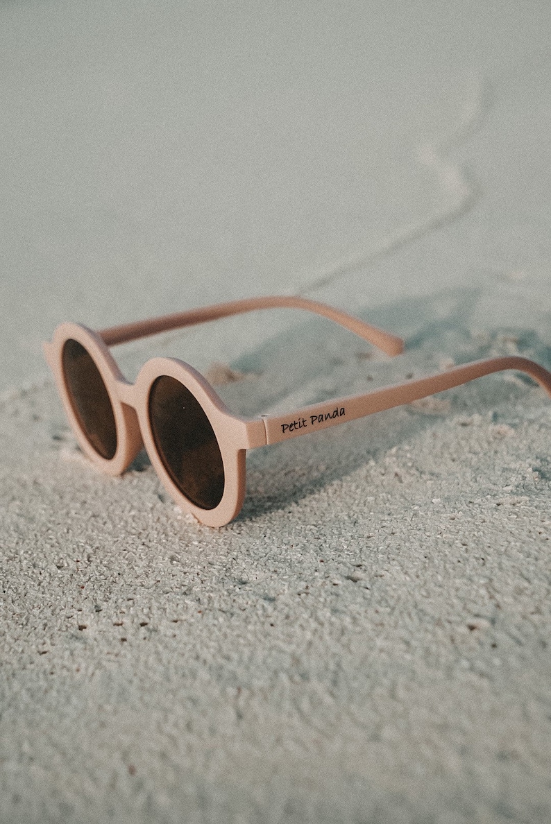 May include: Pink round sunglasses with brown lenses and the text "Petit Panda" on the side.