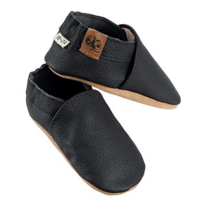 May include: Black leather baby shoes with a brown leather label that says "18-24".