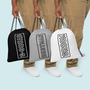 May include: Three drawstring bags in black, gray, and white, each with a black and white rectangular design. The black bag reads "G-SQUAD", the gray bag reads "BESTMAN", and the white bag reads "GROOM". The bags have black drawstrings.