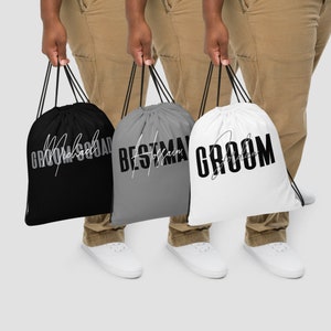 May include: Three drawstring bags with different text printed on them. The bags are black, gray, and white. The text on the bags reads "Groom Squad", "Best Man", and "Groom".