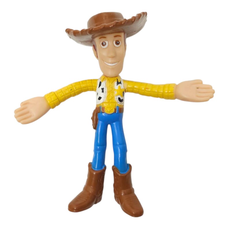 May include: A Woody action figure from the Toy Story franchise. The figure is wearing a brown cowboy hat, yellow shirt, blue trousers, and brown boots. The figure has its arms outstretched and is smiling.