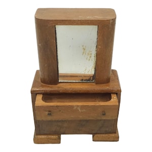 Puede incluir: Un tocador de madera con un cajón y un espejo. El tocador es de color marrón claro y tiene un diseño sencillo.