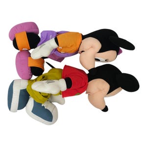 May include: Two plush toys of Mickey Mouse and Minnie Mouse. Mickey is wearing a yellow and orange shirt with a green and yellow jacket. Minnie is wearing a purple shirt with orange and pink shoes.