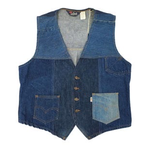 Puede incluir: Un chaleco vaquero patchwork con cuello en V y cierre de botones. El chaleco presenta múltiples tonos de mezclilla azul, con dos bolsillos delanteros y un bolsillo pequeño en el lado derecho. La etiqueta de la marca Levi's es visible.