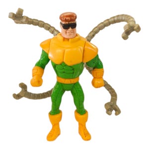 May include: A plastic action figure of a character with brown hair and black sunglasses, wearing a green and yellow suit. The figure features four articulated mechanical tentacles extending from the back, each ending in a three-pronged claw.