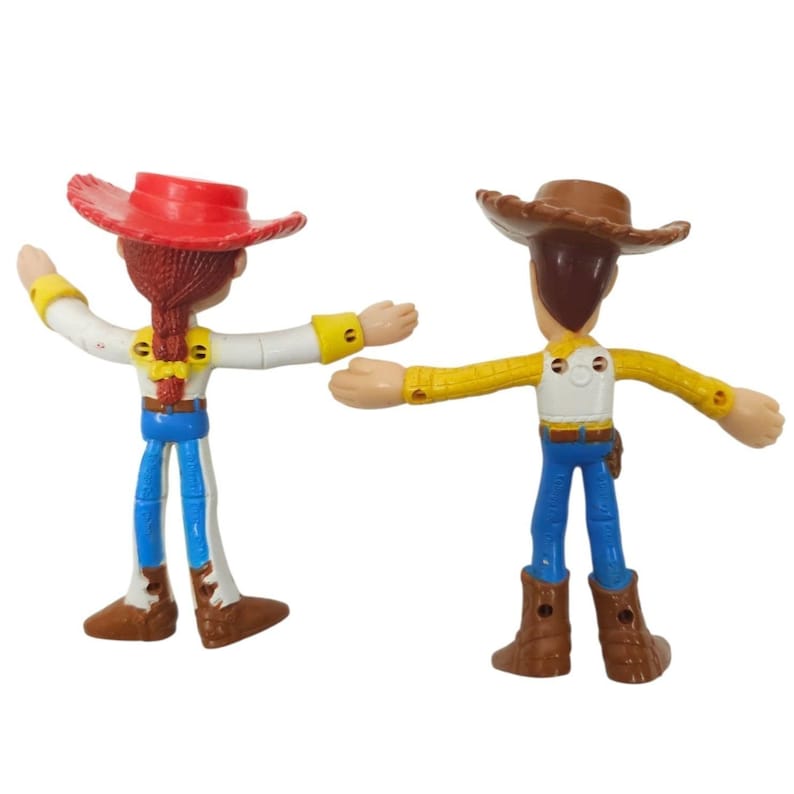 May include: Two Toy Story character figurines, Jessie and Woody, stand side-by-side. Jessie wears a red hat, white shirt, blue trousers, and brown boots. Woody wears a brown hat, yellow shirt, blue trousers, and brown boots. Both have outstretched arms.