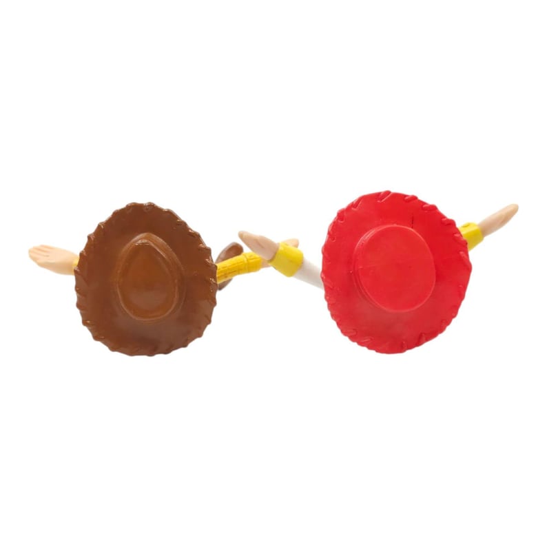 May include: Overhead view of two toy cowboy hats, one brown and one red, with outstretched arms. The brown hat has a wide brim and a rounded crown. The red hat has a smaller brim and a flat top. Both have yellow details.