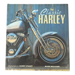 May include: A book cover featuring a classic Harley-Davidson motorcycle. The title "The Classic Harley" is displayed in large, stylized text. The image showcases the motorcycle's chrome details and front wheel against a blue background.