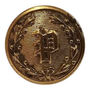 May include: A gold-coloured button featuring a raised letter "P" encircled by a wreath of leaves. The button has a textured surface.