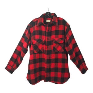 May include: A red and black plaid flannel shirt with long sleeves and button-up closure. The shirt has two large pockets on the front.