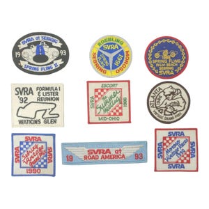 May include: A collection of vintage SVRA racing patches. The patches feature various designs, including race cars, track layouts, and text such as "Spring Fling" and "Road America." Colors include blue, red, white, and yellow.