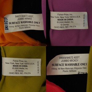 May include: Four plush toys with labels indicating they are surface washable. The labels include the product name, manufacturer, and country of origin. The toys are in the colors orange, purple, yellow, and red.